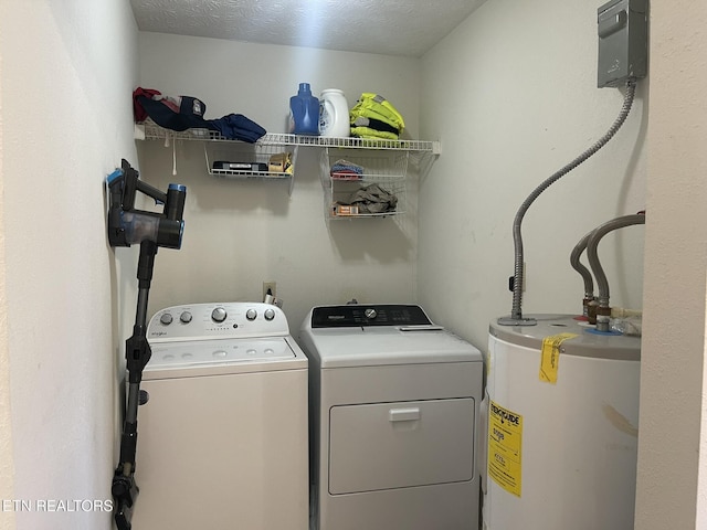 laundry area with water heater, laundry area, a textured ceiling, and washer and clothes dryer