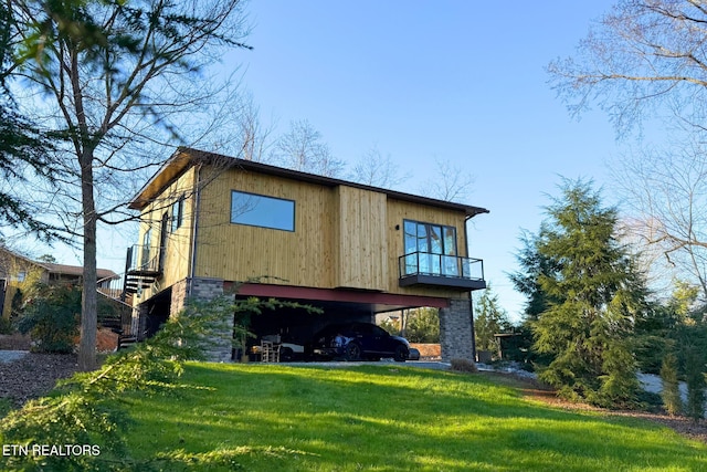 rear view of house featuring a carport, stairway, and a lawn