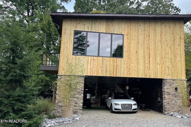 exterior space featuring stone siding, a carport, and gravel driveway