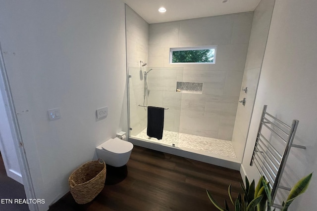 full bath with a tile shower, recessed lighting, toilet, and wood finished floors