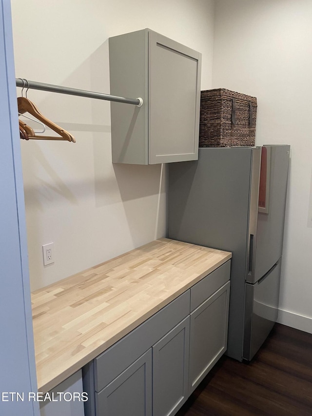 kitchen featuring wood counters, dark wood-type flooring, gray cabinetry, and freestanding refrigerator