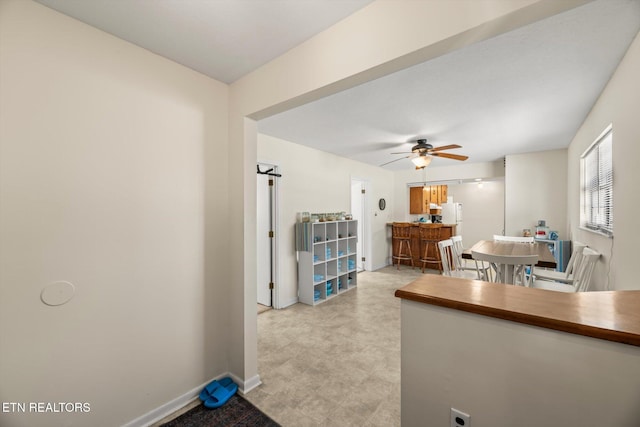 interior space featuring baseboards, a ceiling fan, and freestanding refrigerator