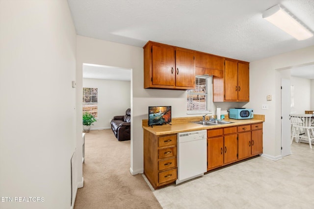 kitchen with a sink, light countertops, a textured ceiling, dishwasher, and brown cabinets