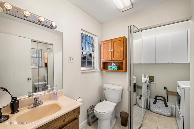 bathroom with tile patterned floors, toilet, washing machine and dryer, and plenty of natural light