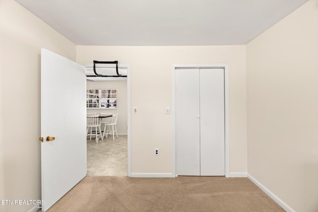 unfurnished bedroom featuring baseboards, carpet floors, and a closet