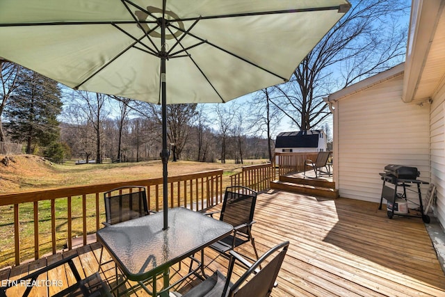 deck featuring outdoor dining space, a lawn, and a grill