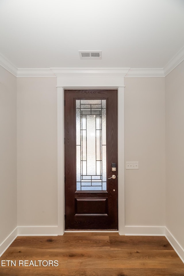 foyer entrance featuring visible vents, wood finished floors, baseboards, and ornamental molding