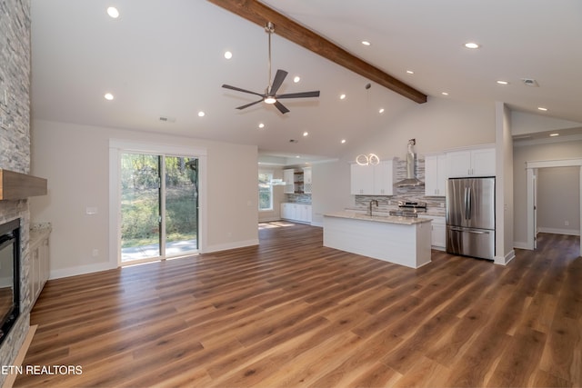 kitchen with beam ceiling, a fireplace, white cabinets, appliances with stainless steel finishes, and open floor plan