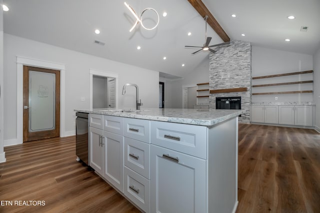 kitchen with visible vents, beam ceiling, a sink, dark wood finished floors, and a stone fireplace