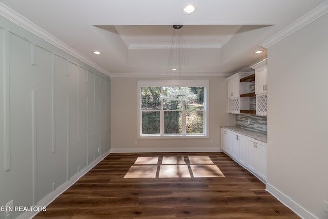 unfurnished dining area with recessed lighting, crown molding, a raised ceiling, and dark wood-style flooring