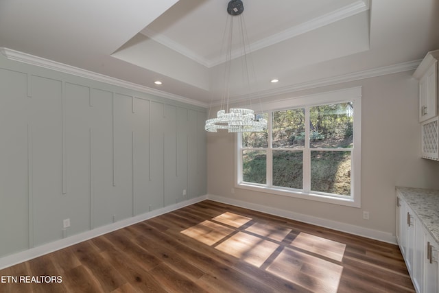 unfurnished dining area featuring a raised ceiling, dark wood finished floors, and ornamental molding