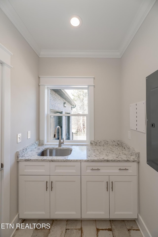 kitchen featuring a sink, light stone countertops, ornamental molding, and white cabinetry