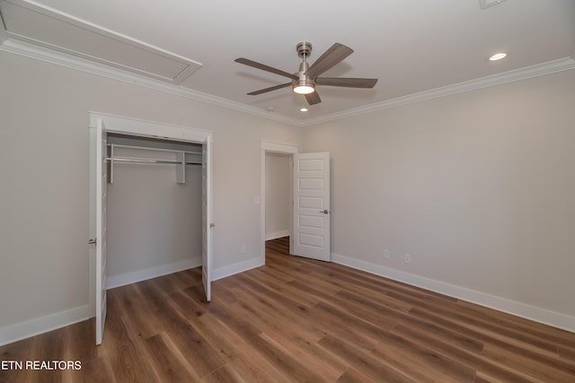 unfurnished bedroom with attic access, wood finished floors, and ornamental molding