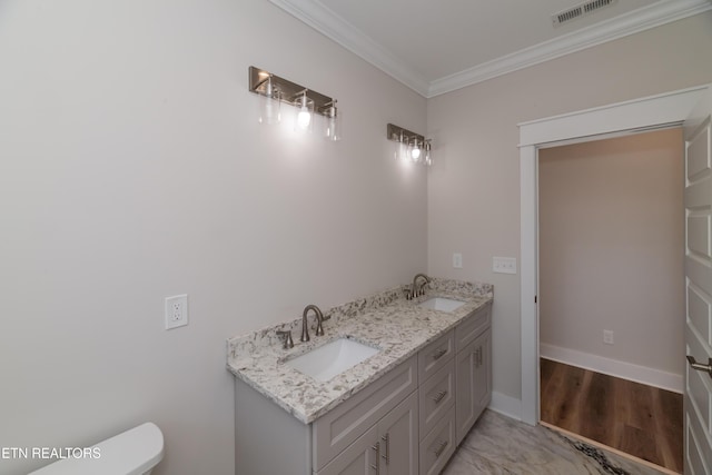 bathroom featuring toilet, ornamental molding, visible vents, and a sink