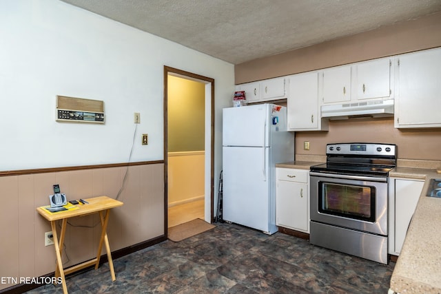 kitchen with a wainscoted wall, freestanding refrigerator, stainless steel range with electric cooktop, light countertops, and under cabinet range hood