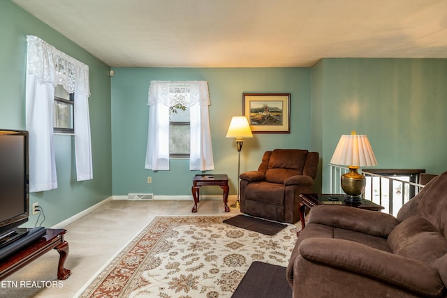 carpeted living area featuring visible vents and baseboards