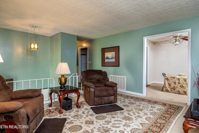 living room with visible vents, carpet, baseboards, a textured ceiling, and a ceiling fan