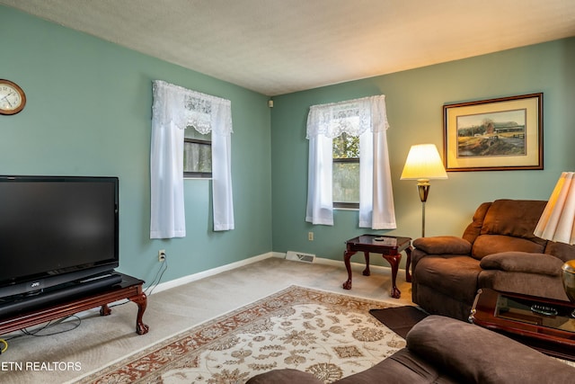 living area featuring visible vents, baseboards, and carpet