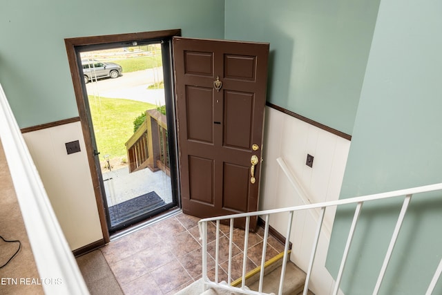 tiled foyer entrance with wainscoting and stairs