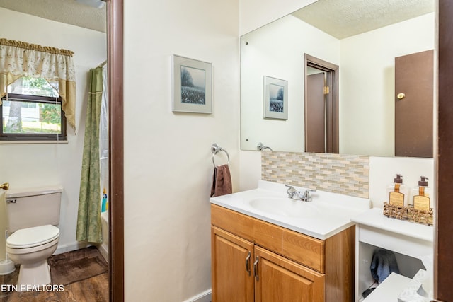 full bathroom featuring toilet, vanity, decorative backsplash, wood finished floors, and a textured ceiling