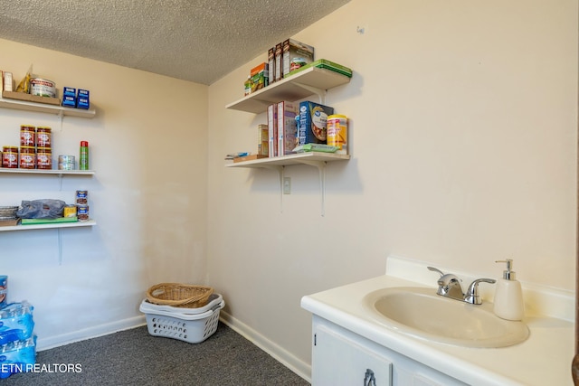 bathroom with vanity, baseboards, and a textured ceiling