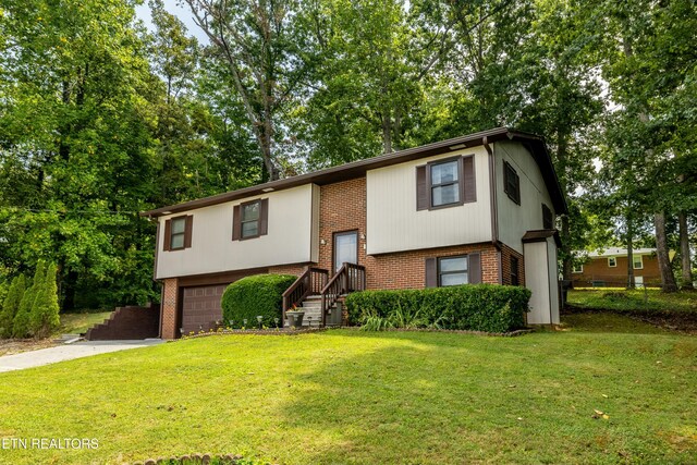 split foyer home with brick siding, driveway, an attached garage, and a front yard