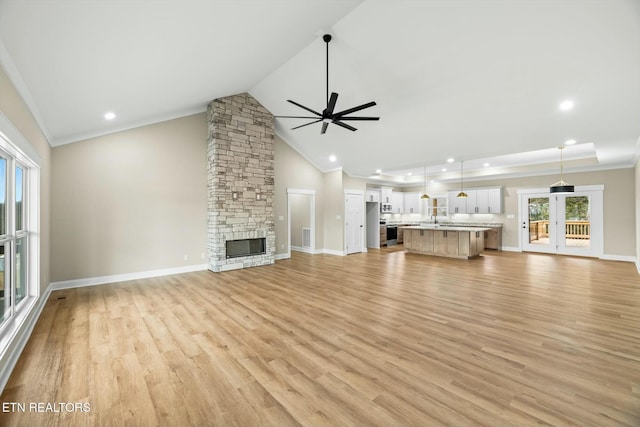 unfurnished living room with light wood-style flooring, baseboards, ceiling fan, and a fireplace