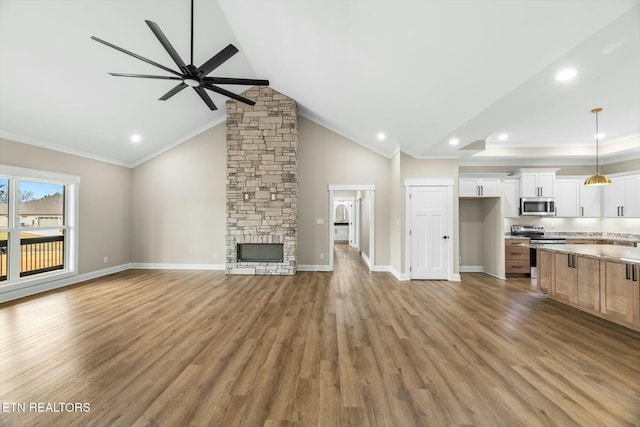 unfurnished living room featuring ceiling fan, baseboards, a stone fireplace, and wood finished floors