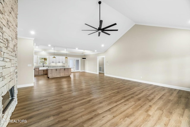 unfurnished living room with wood finished floors, a ceiling fan, baseboards, visible vents, and a fireplace