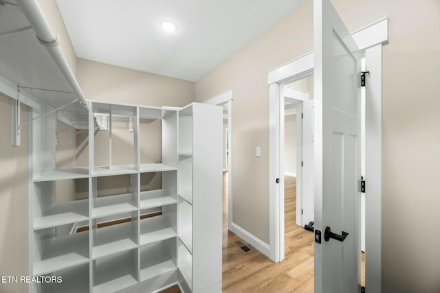 walk in closet with wood finished floors