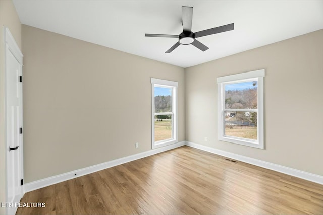 spare room with a ceiling fan, light wood-style floors, baseboards, and visible vents