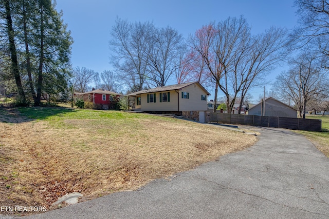 view of front of property featuring driveway, a front lawn, and fence