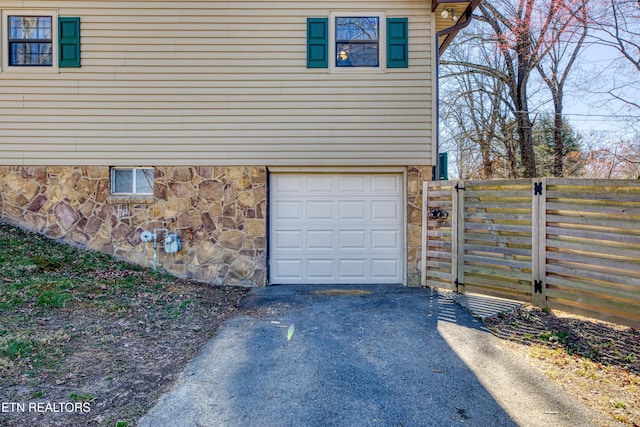 garage featuring aphalt driveway and fence