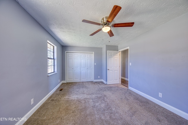 unfurnished bedroom featuring a textured ceiling, a closet, carpet, baseboards, and ceiling fan