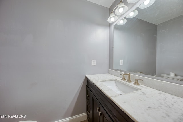 bathroom featuring toilet, vanity, and baseboards