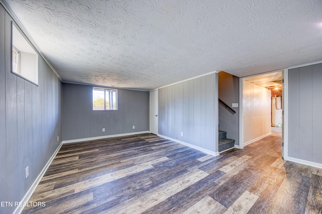 spare room featuring stairway, a textured ceiling, baseboards, and wood finished floors