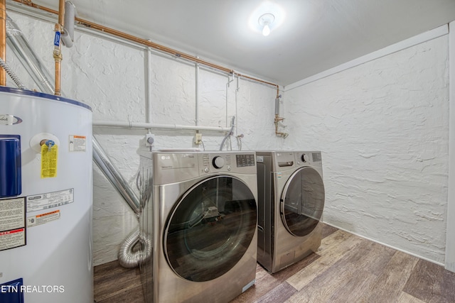 washroom featuring electric water heater, wood finished floors, a textured wall, laundry area, and washing machine and clothes dryer