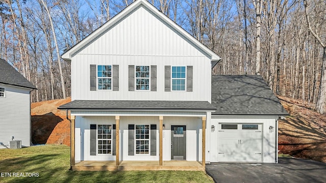 view of front of home featuring central AC unit, driveway, roof with shingles, an attached garage, and a front lawn