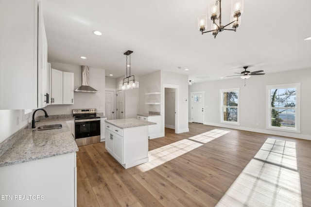 kitchen featuring a sink, light wood-style floors, stainless steel electric stove, and wall chimney range hood