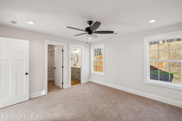 unfurnished bedroom with recessed lighting, a walk in closet, baseboards, and carpet flooring