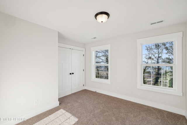 unfurnished bedroom featuring visible vents, baseboards, a closet, and carpet flooring