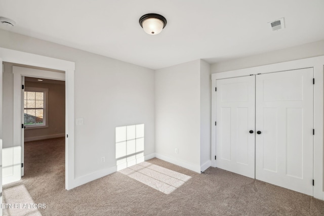 unfurnished bedroom with carpet, visible vents, and baseboards