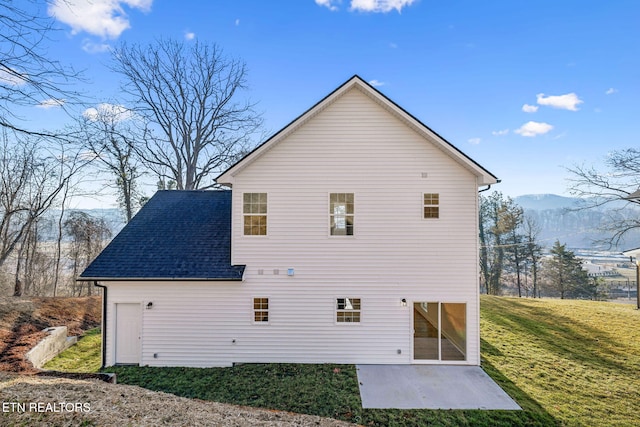 rear view of property featuring a mountain view, a lawn, and a shingled roof