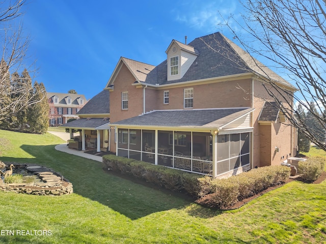 back of house featuring a patio, a yard, brick siding, and a sunroom