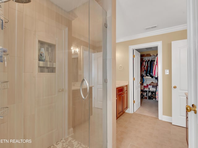 full bath featuring tile patterned floors, a walk in closet, a stall shower, and crown molding