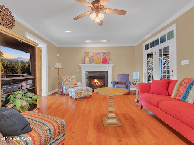 living area featuring wood finished floors, baseboards, french doors, a glass covered fireplace, and crown molding