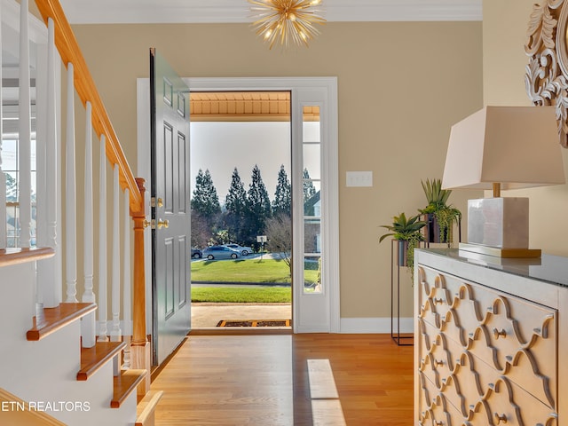 foyer entrance featuring crown molding, baseboards, a chandelier, stairs, and wood finished floors