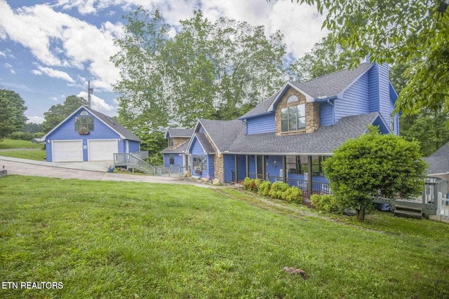 view of front of house featuring an outbuilding, a front yard, covered porch, a shingled roof, and a detached garage