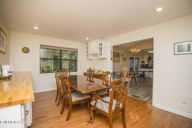 dining space featuring recessed lighting, a notable chandelier, baseboards, and light wood-type flooring