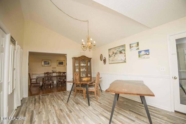 dining room with a chandelier, lofted ceiling, and wood finished floors